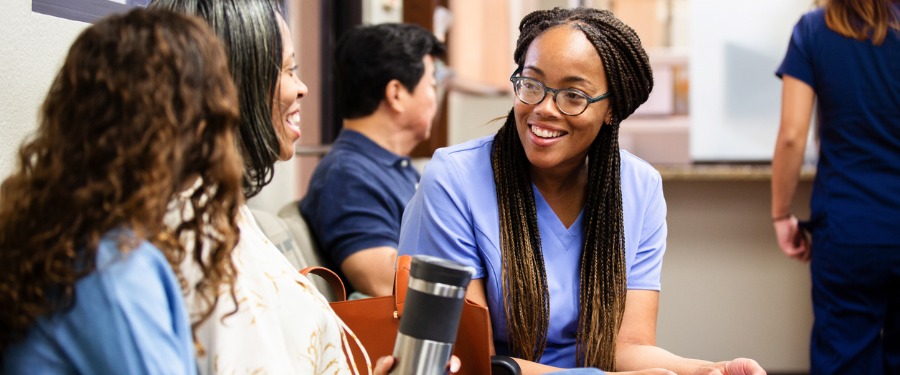 Female patients talk to female doctor in waiting room