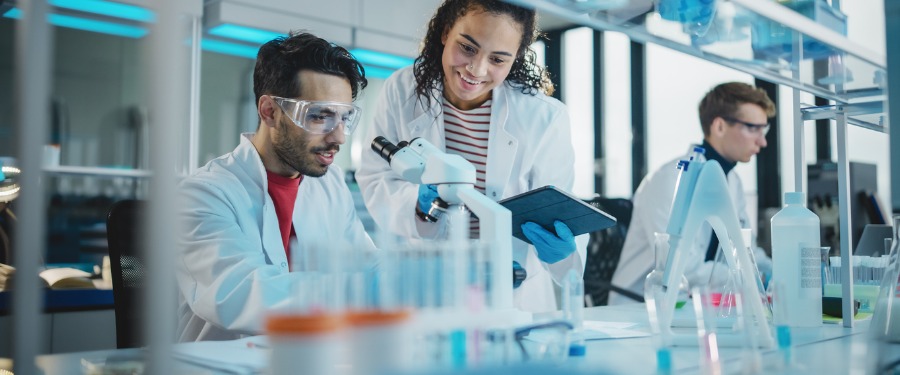 Two lab researchers looking at a microscope